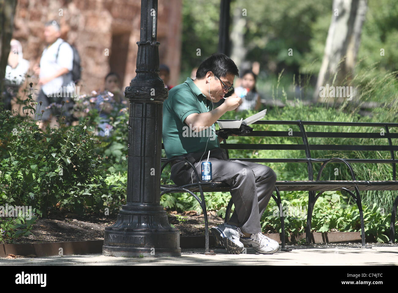 Asian man eating take-out dans le parc Banque D'Images