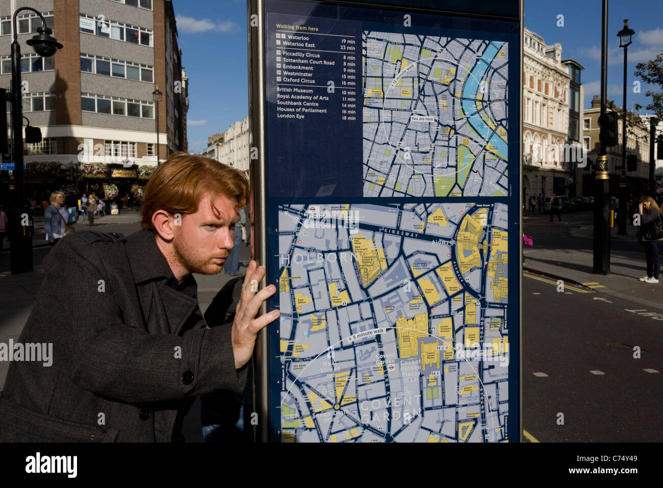 Un visiteur examine l'un des nombreux plans de rues de Londres, ce l'un situé près de la station de métro Leicester Square. Banque D'Images