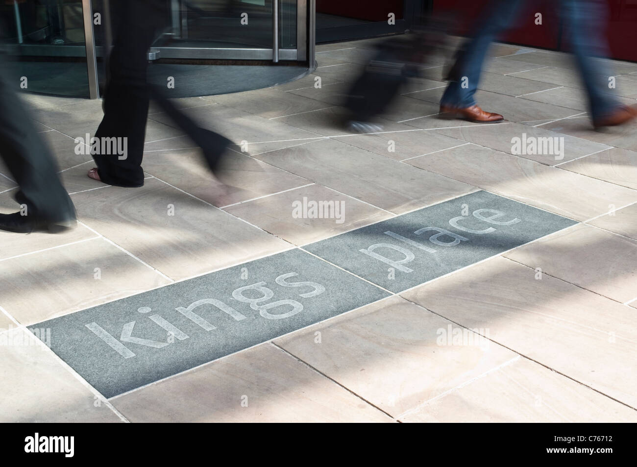 L'entrée de Kings Place à Londres, avec des portes tournantes, les pieds des gens de passage flou, et la construction d'un logo. Banque D'Images