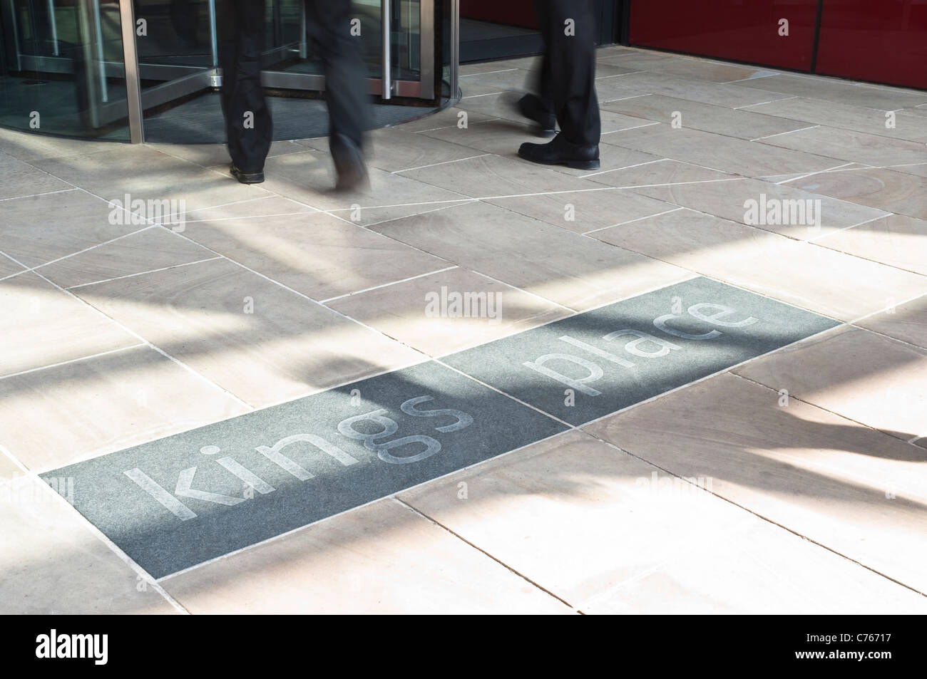 L'entrée de Kings Place à Londres, avec des portes tournantes, les pieds des deux floue passant d'affaires, et la construction d'un logo. Banque D'Images