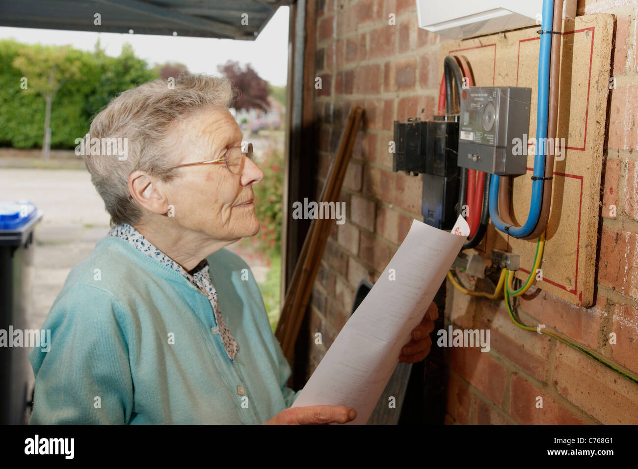 Femme âgée à la recherche et vérification des factures de services publics d'électricité et de gaz avec le compteur en cas de divergences Banque D'Images