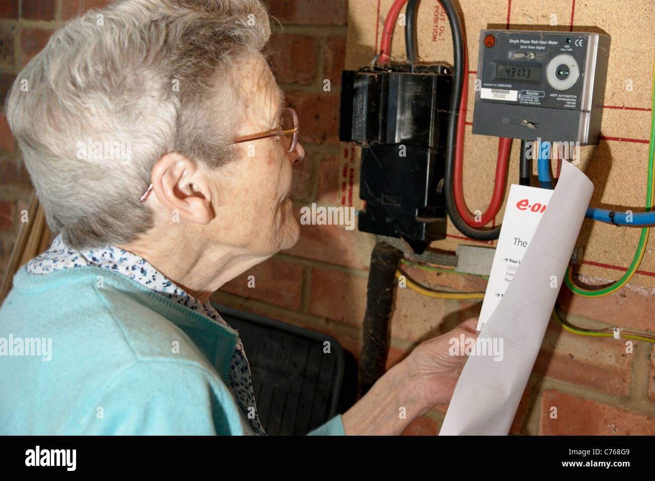 Femme âgée à la recherche et vérification des factures de services publics d'électricité et de gaz avec le compteur en cas de divergences Banque D'Images