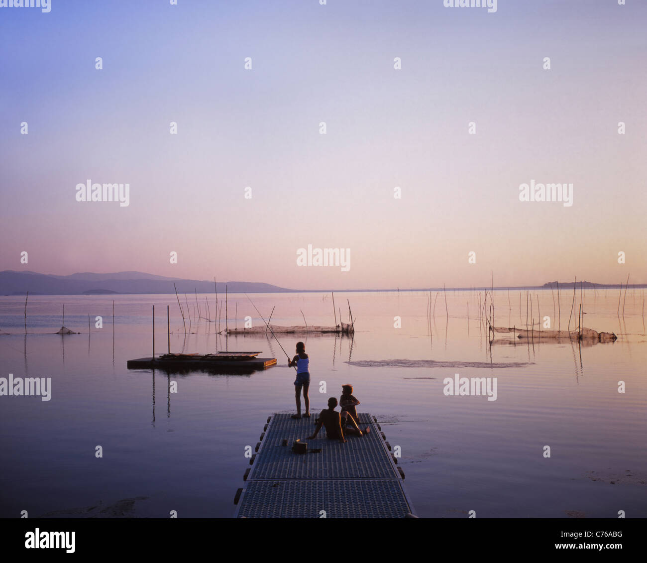 Les enfants de la pêche au large de l'embarcadère du lac, Trasemeno, Ombrie, Italie Banque D'Images