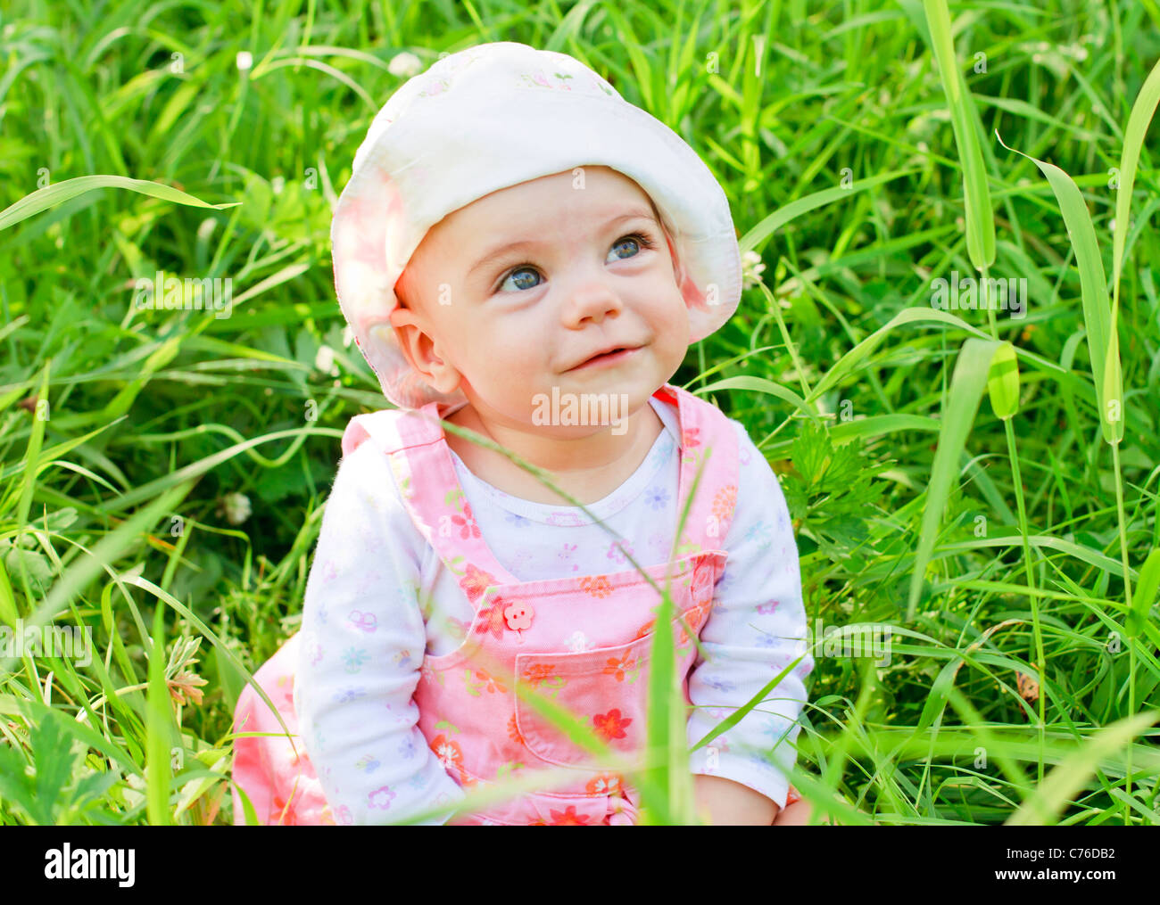 Happy Baby Girl with blue eyes lying on grass Banque D'Images
