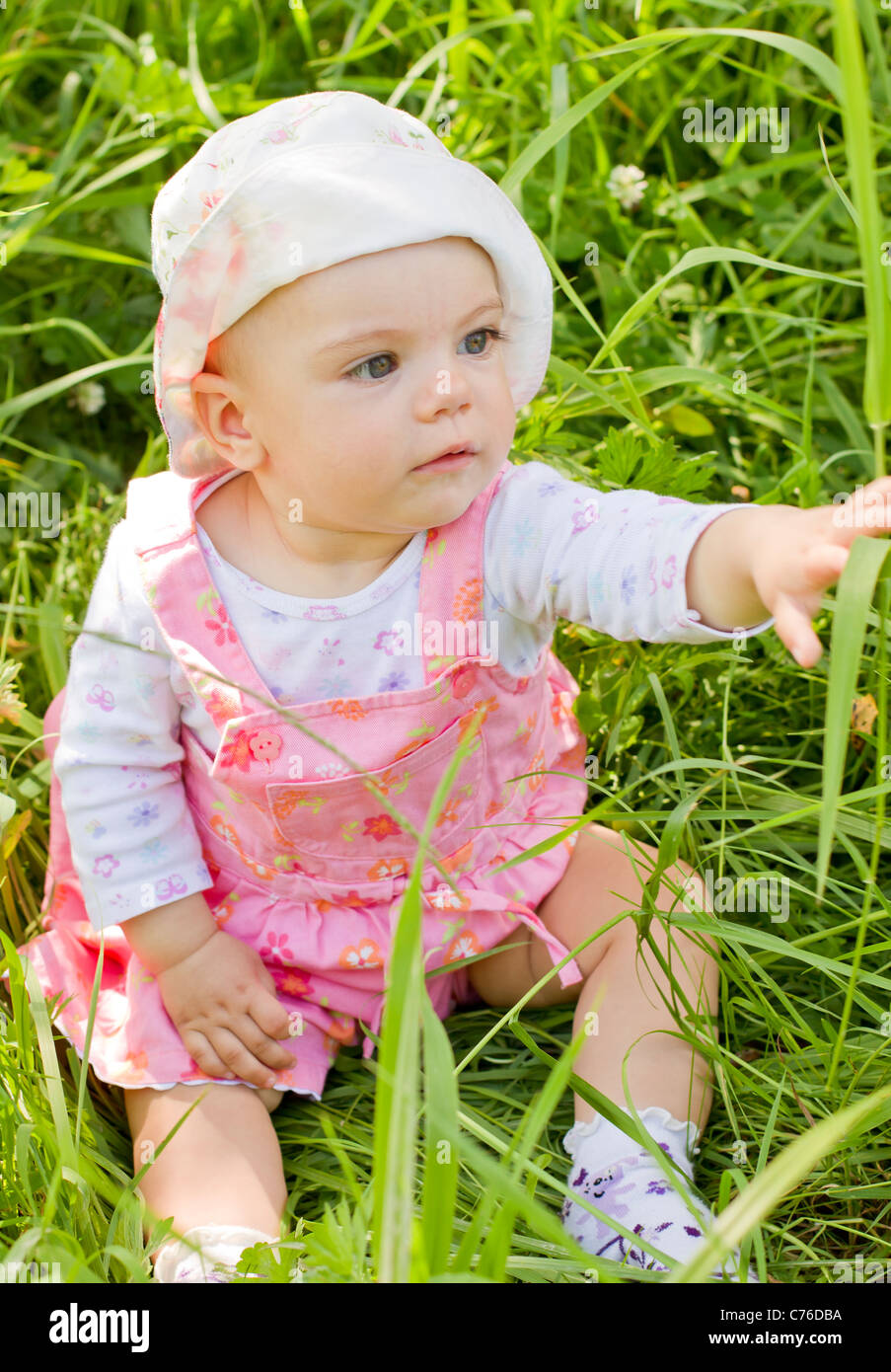 Curieux baby girl on grass Banque D'Images