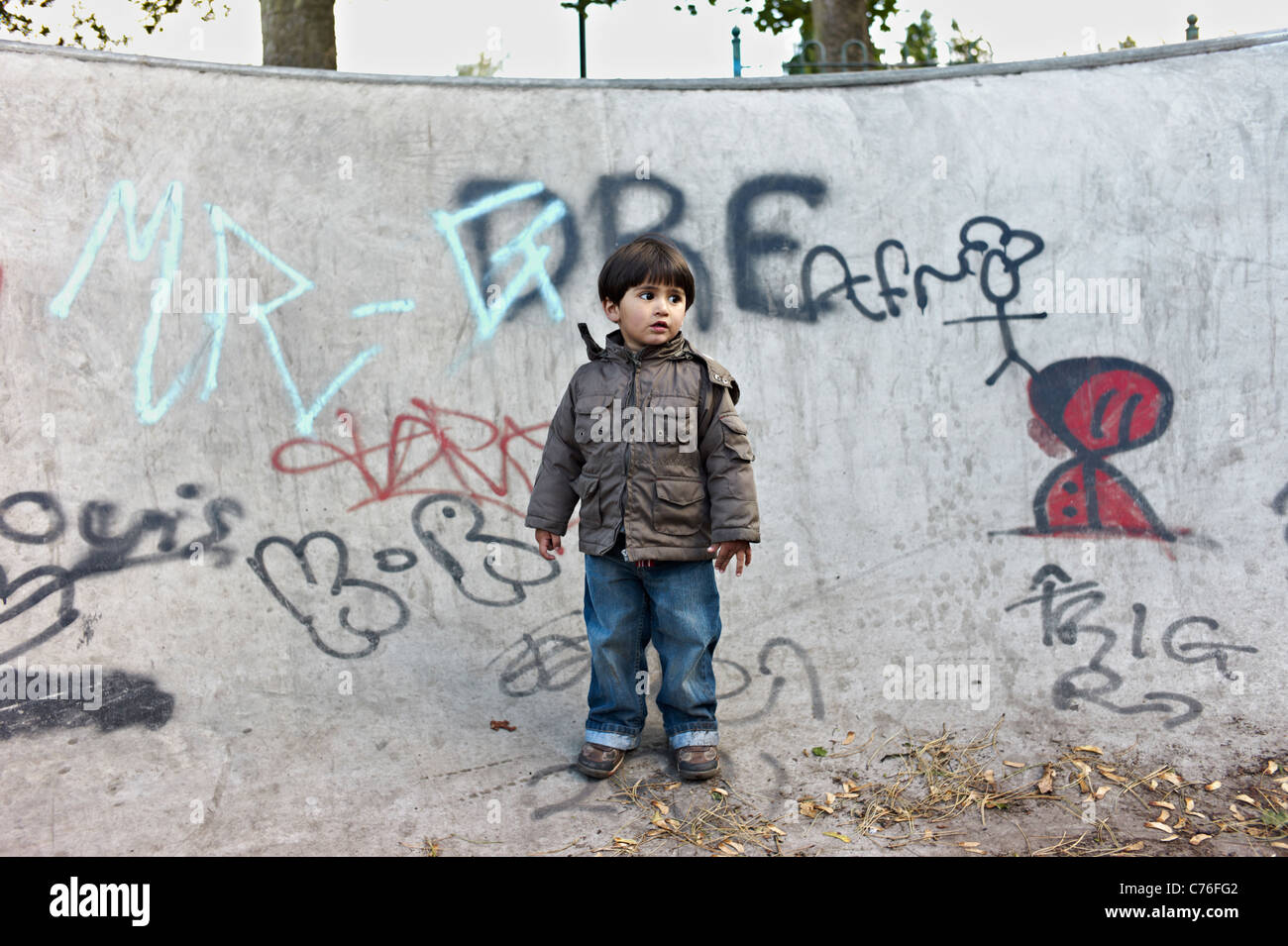 Mixed Race toddler semble perdu dans un skate park à Birmingham, entouré par le graffiti. Banque D'Images