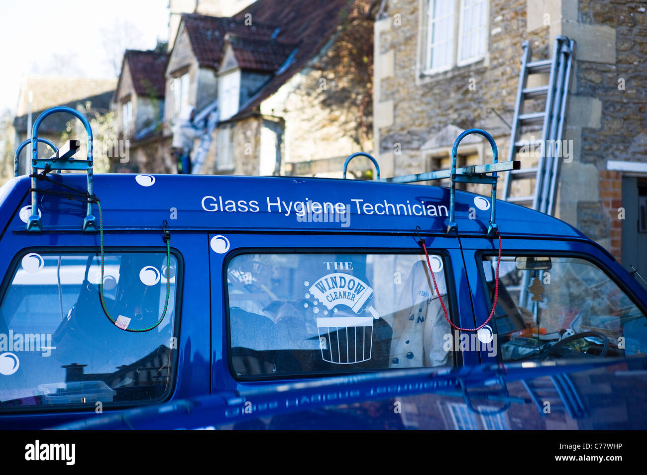 Blue van appartenant à "verre" ou technicien hygiène nettoyant pour vitres à l'œuvre dans village Banque D'Images