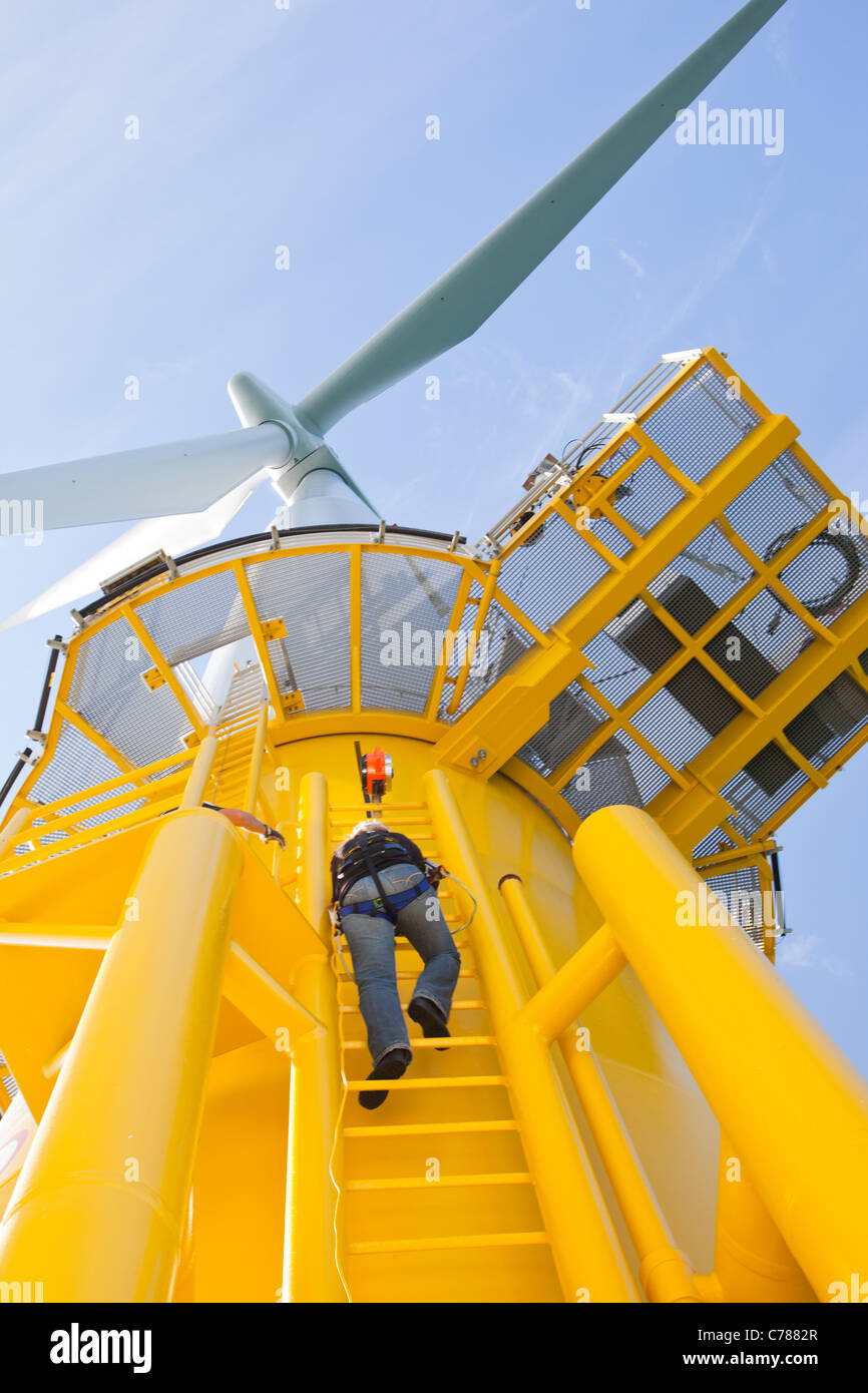 Un travailleur l'ascension d'une éolienne à l'éolien offshore Walney. Banque D'Images