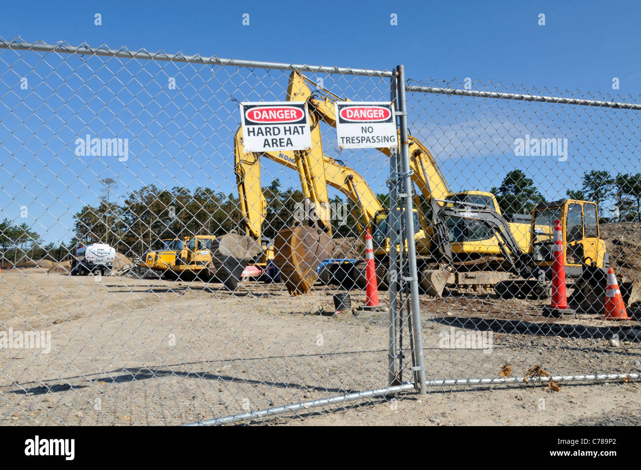 Site de construction d'équipement lourd entouré de clôture métallique avec attention, danger et casque de signes. USA Banque D'Images