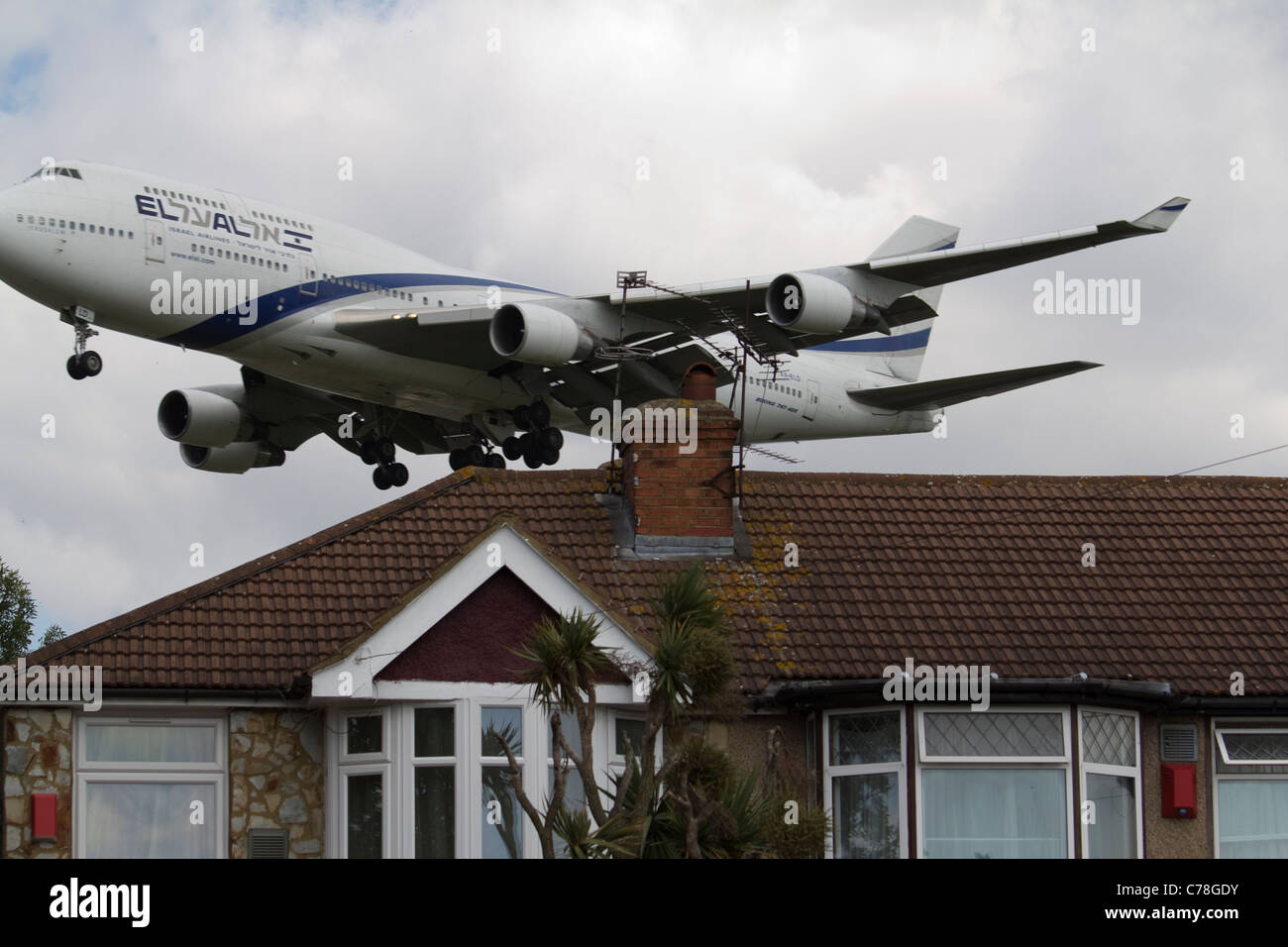 Un avion El Al volant à basse altitude approche de l'aéroport d'Heathrow, passant au-dessus de logements résidentiels et soulignant les préoccupations concernant la pollution sonore Banque D'Images