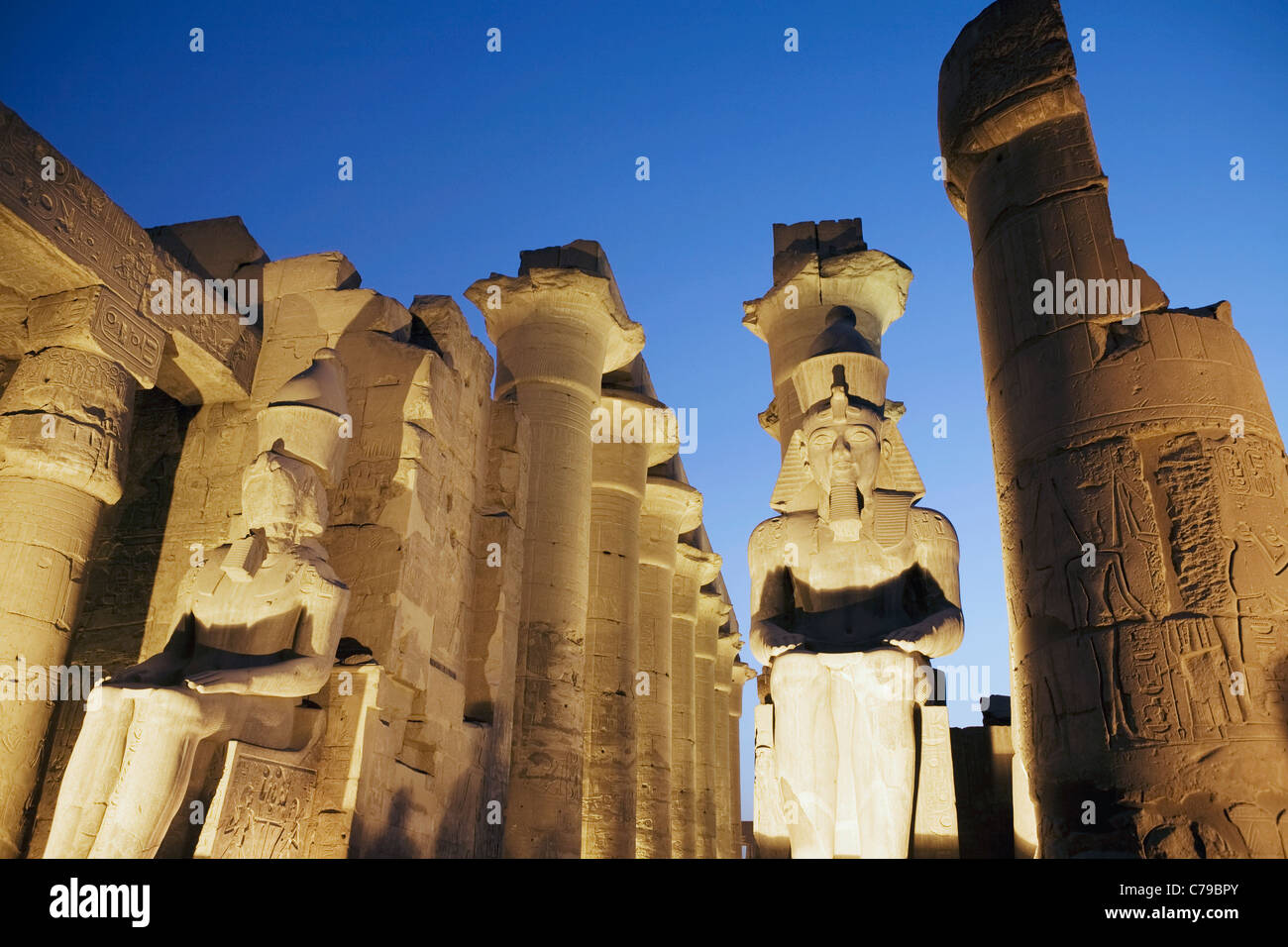 Assis colossales statues de Ramsès II et de la colonnade d'Amenhotep III dans la nuit, le temple de Louxor, Louxor, Egypte Banque D'Images