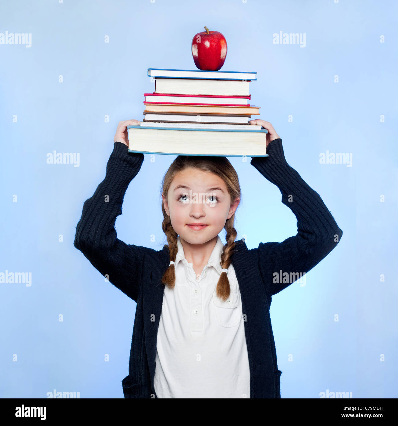 Portrait of Girl (10-11) holding pile de livres et apple on head Banque D'Images