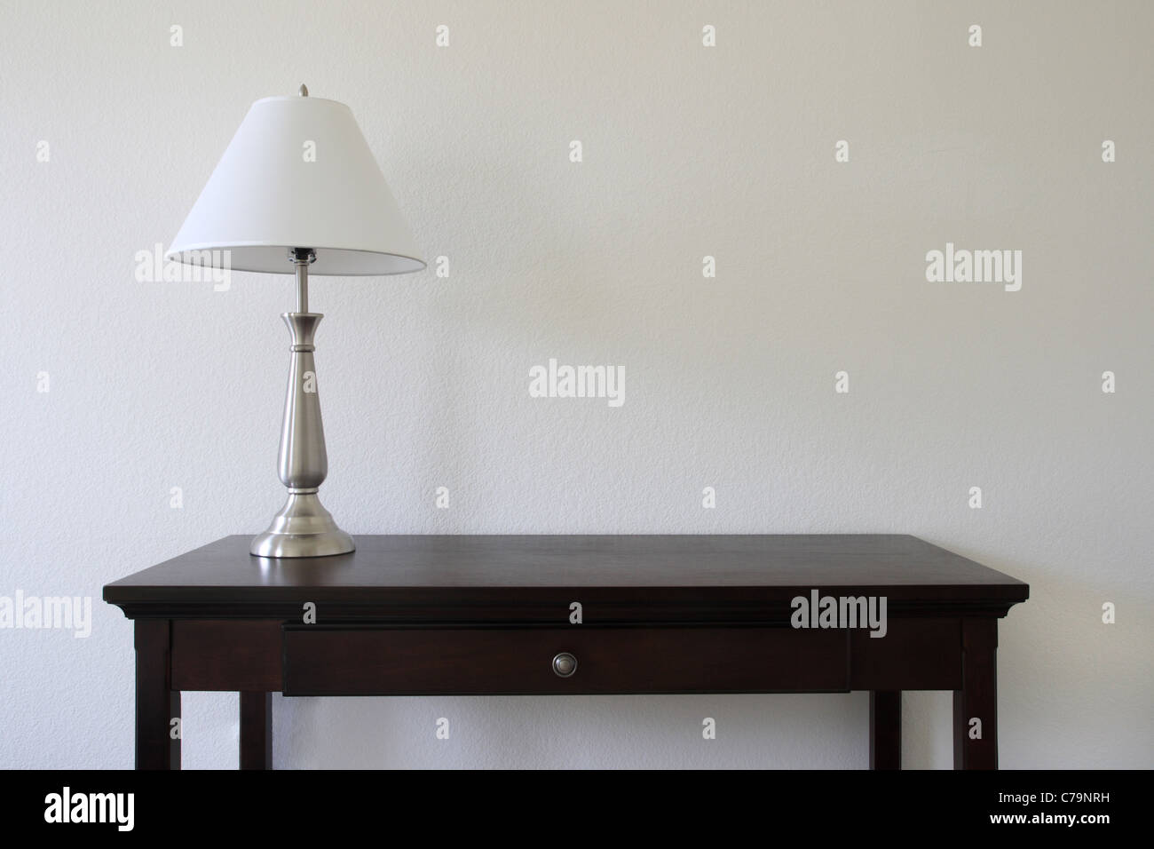 Lampe de table d'argent assis sur une table en bois avec un mur blanc en arrière-plan et l'espace de copie Banque D'Images