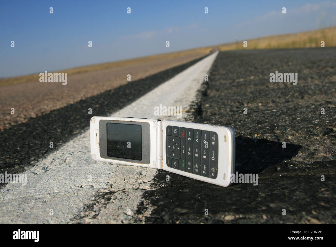 Replier blanc téléphone portable abandonné sur le bord de la route Banque D'Images