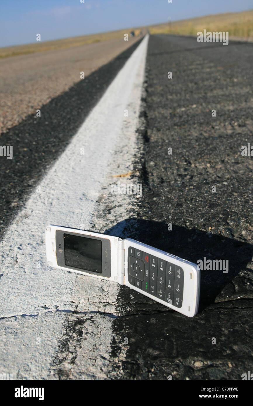 Vertical image du pli jusqu'à blanc téléphone cellulaire a chuté sur la route Banque D'Images