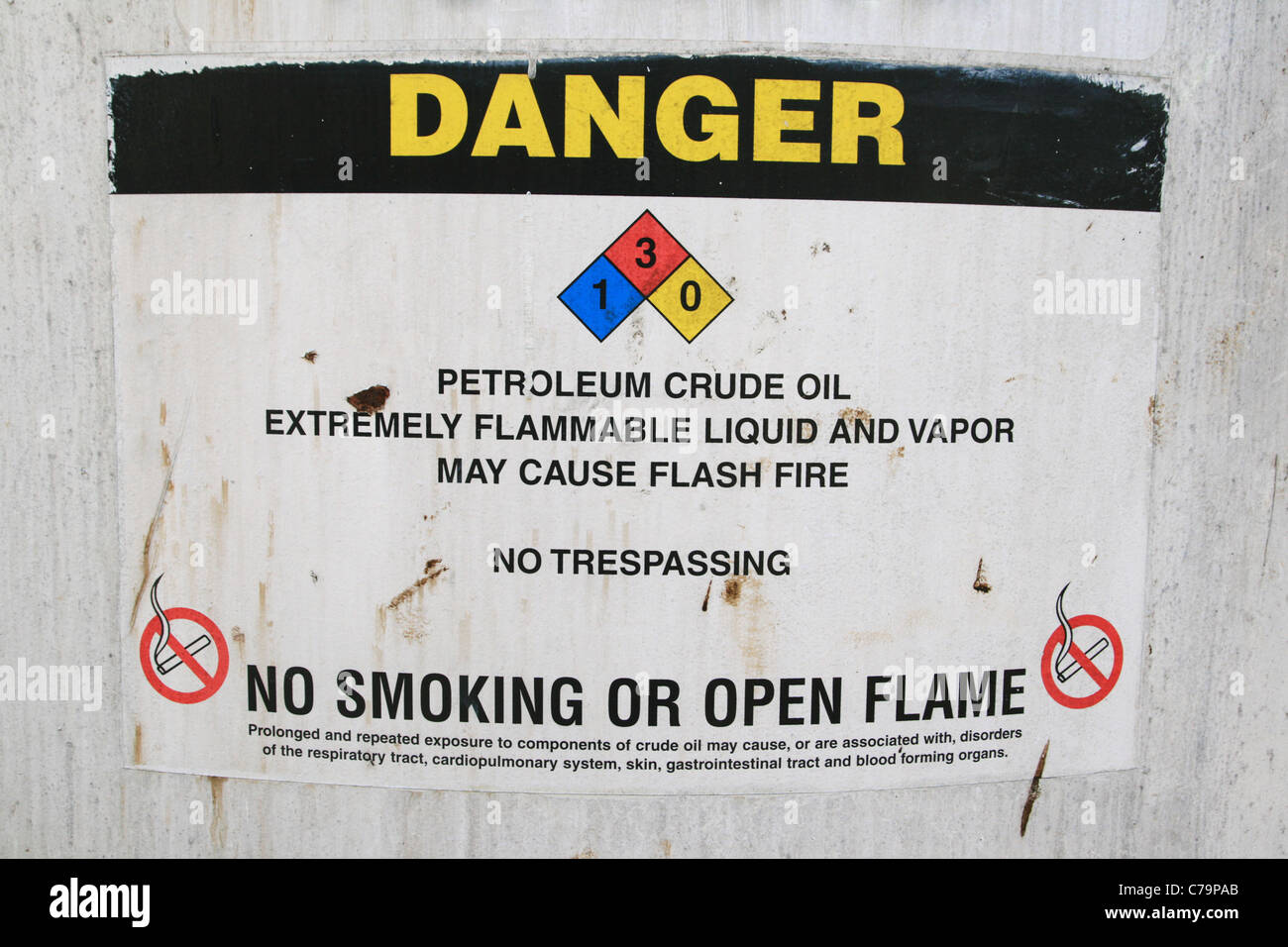 Pétrole brut Le signe de danger sur le côté d'un vieux réservoir d'huile de pétrole brut Banque D'Images