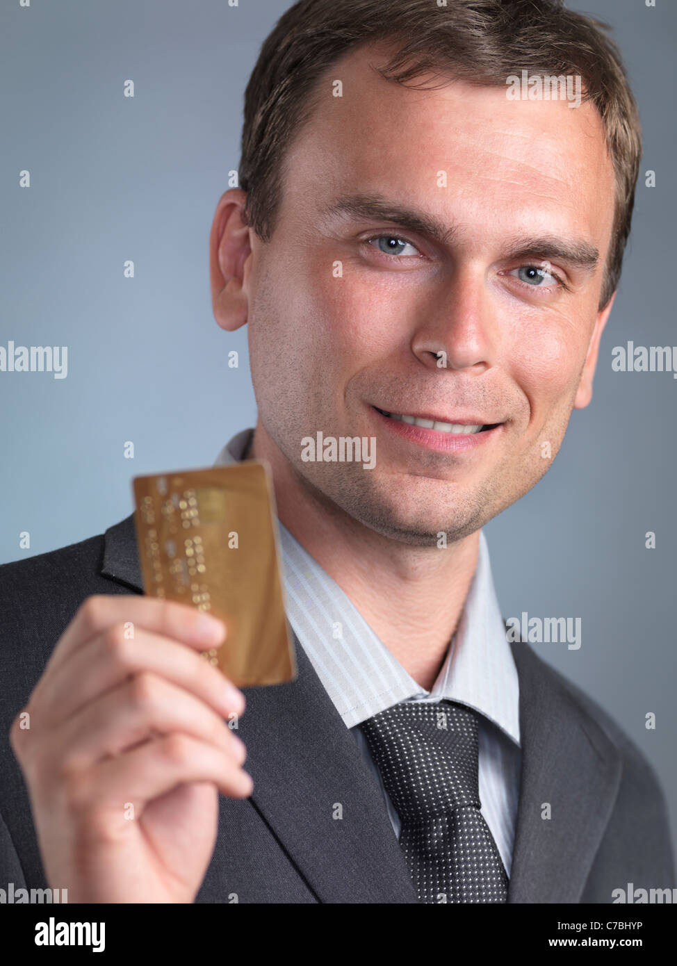 Smiling businessman holding a carte de crédit or dans ses mains Banque D'Images