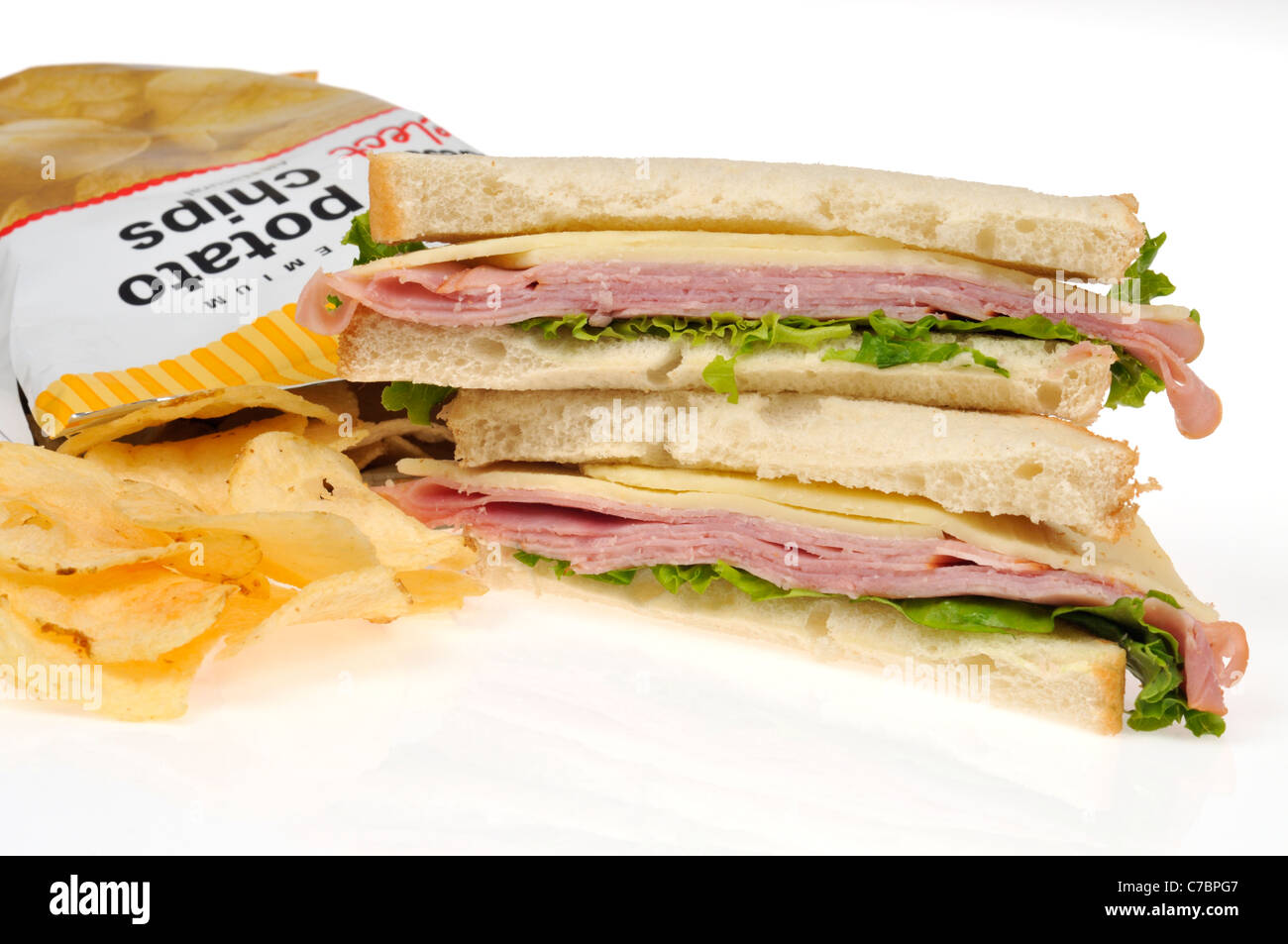 Sandwich au jambon et au fromage avec salade sur le pain blanc et sac de croustilles de pommes de terre sur fond blanc. Banque D'Images