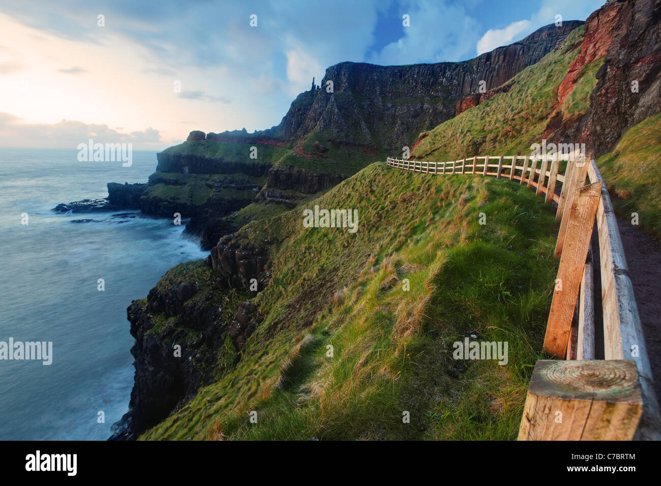 Cliffside clôturé trail sur Benbane Head près de Sunset, Giant's Causeway, comté d'Antrim, en Irlande du Nord, Royaume-Uni Banque D'Images
