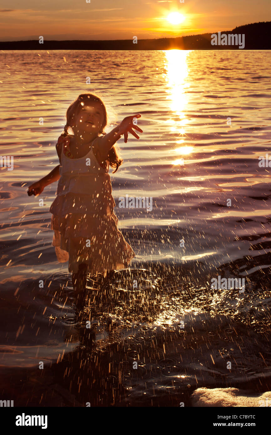 Petite fille heureuse aux projections d'eau dans le lac Banque D'Images