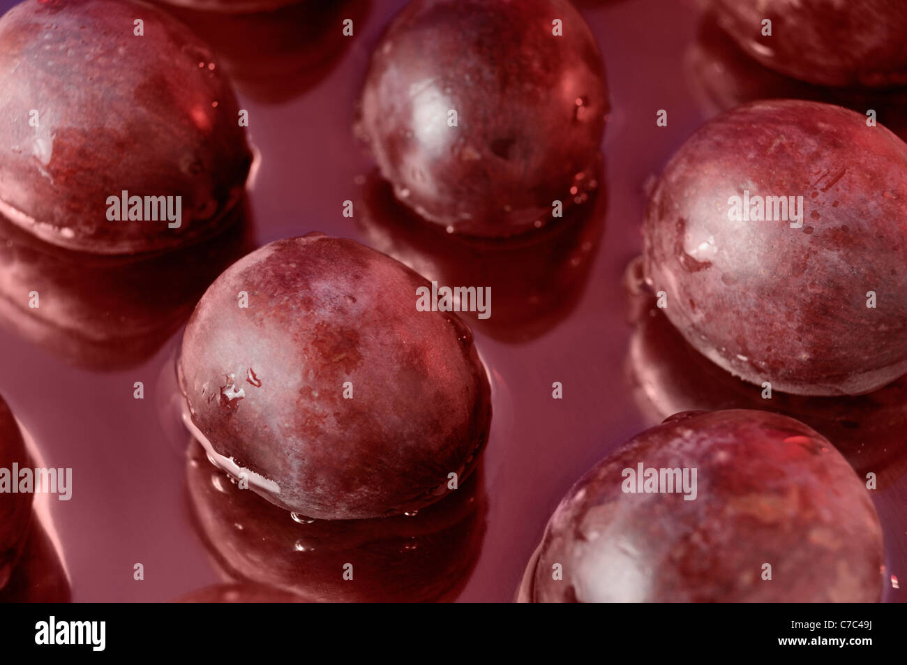 Les raisins rouges dans le jus de raisin. Contexte artistique Banque D'Images