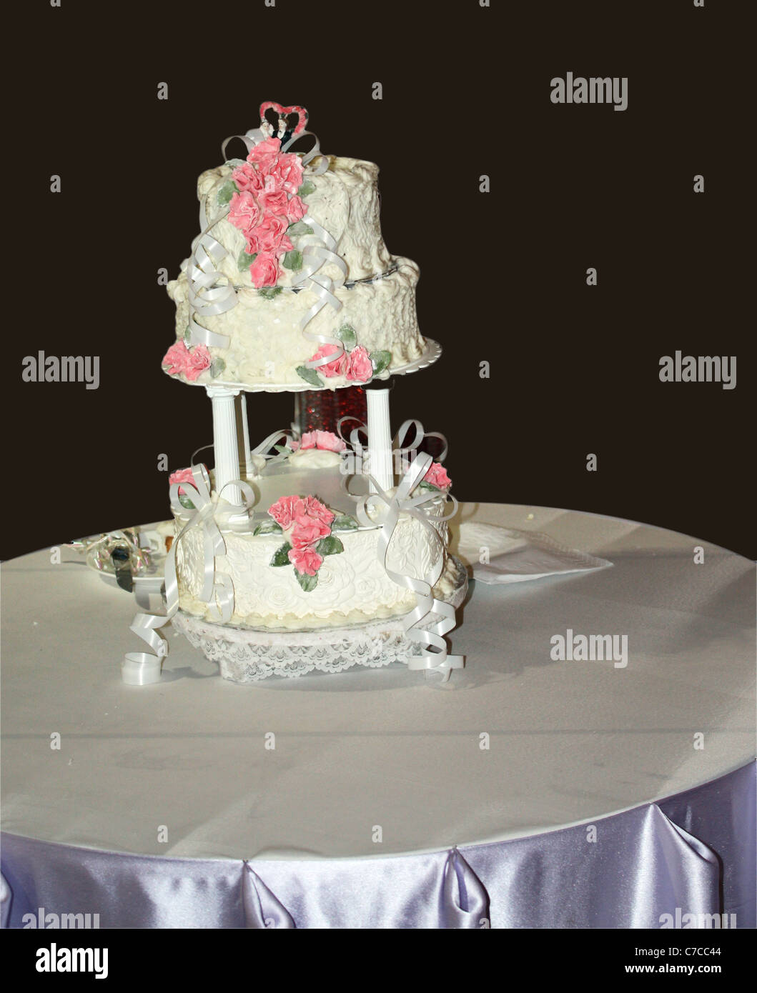 Un gâteau de mariage crémeux blanc placé sur une table de cu dans fond noir Banque D'Images