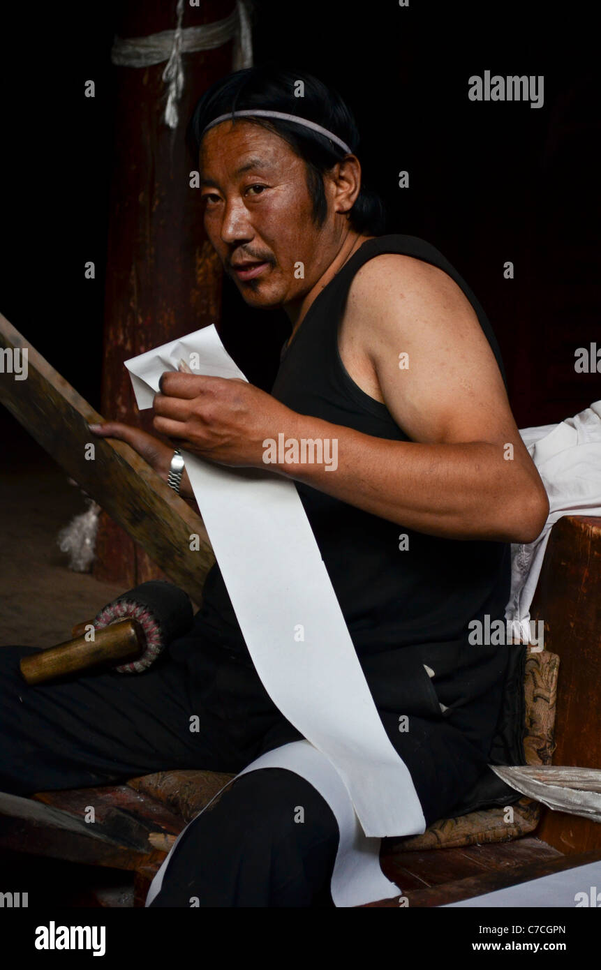 Un homme fait une pause pendant l'impression de textes bouddhistes à la lamaserie bouddhiste tibétain à Dege, Sichuan, Chine Banque D'Images