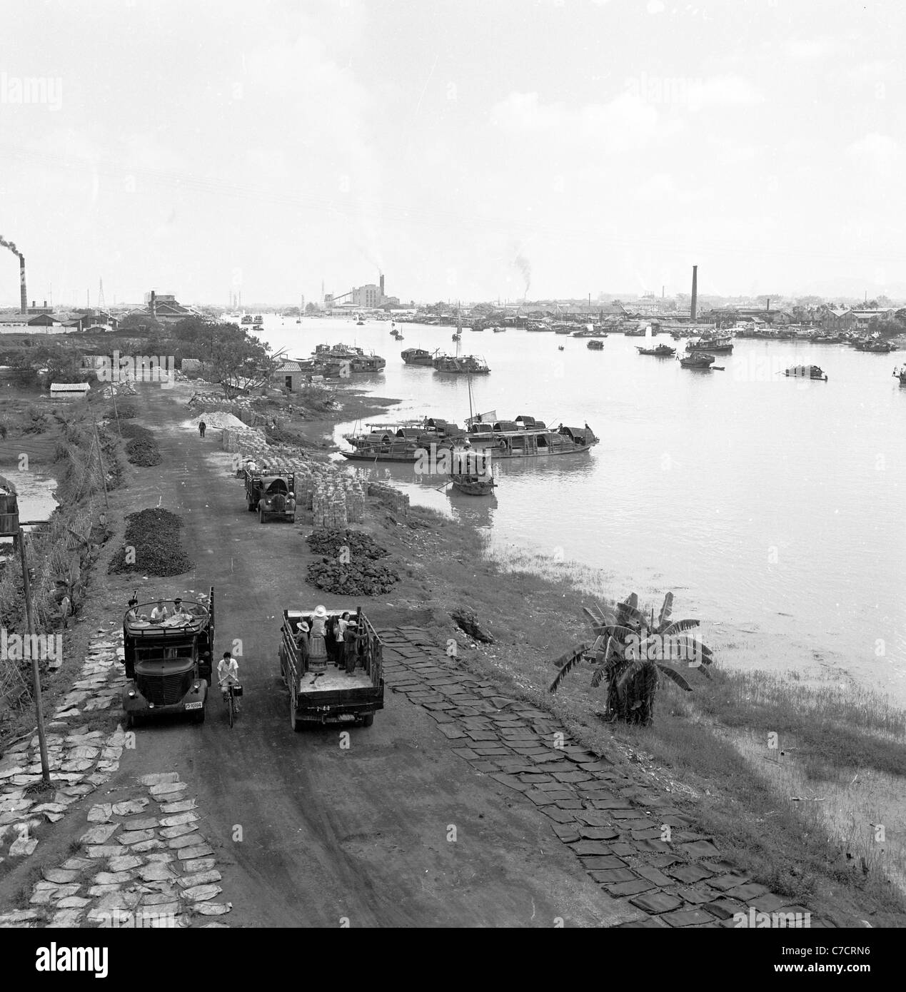 Années 1950. Tableau historique des camions le long d'une rivière, la Chine. Banque D'Images
