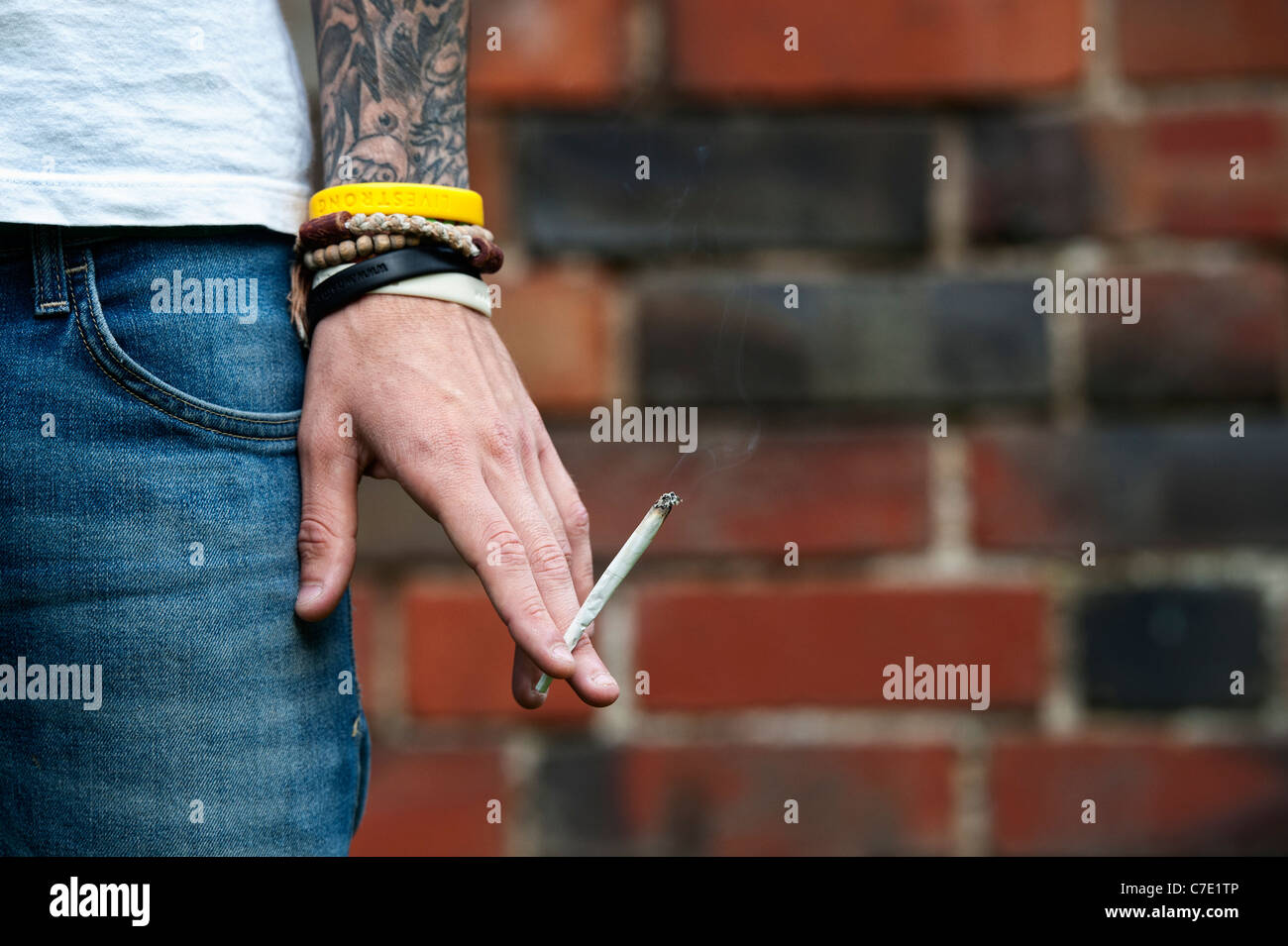 L'adolescent tatoué tenant un joint de cannabis Banque D'Images