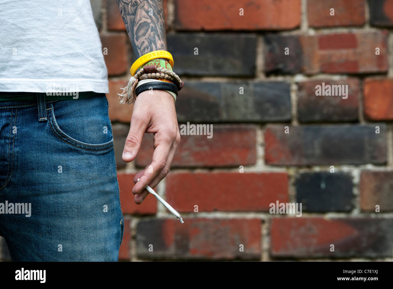 L'adolescent tatoué tenant un joint de cannabis Banque D'Images
