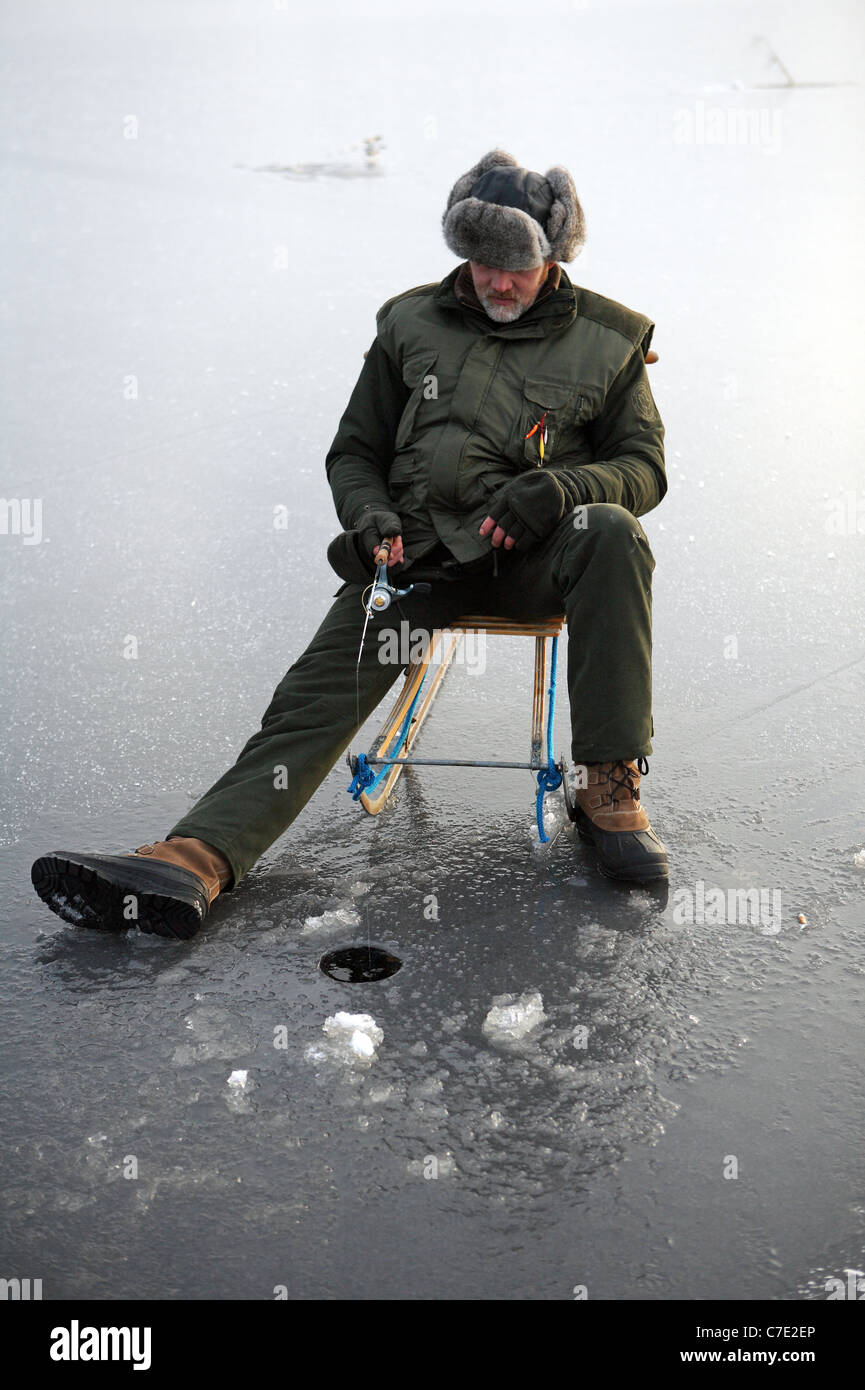 L'homme pêche sur glace dans le lac Stora Bellen, Belloe, Suède Banque D'Images