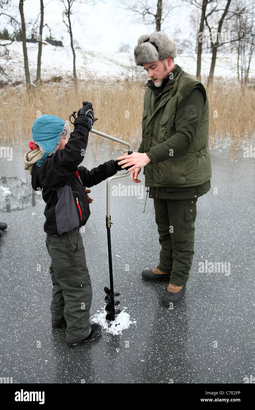Un garçon pêche sur glace le forage d'un trou dans le lac Stora Bellen, Belloe, Suède Banque D'Images