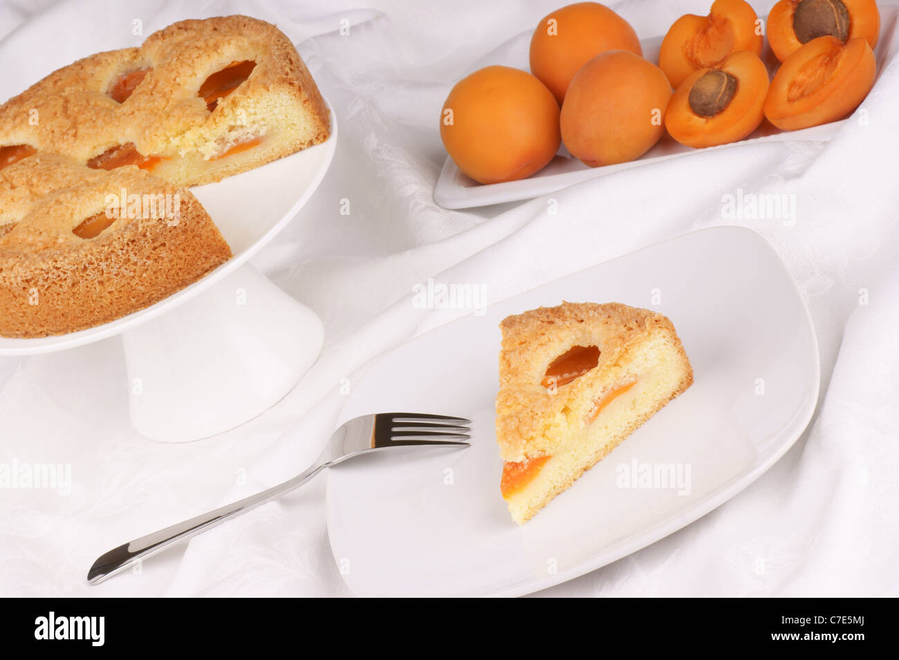 Une tranche de Tarte aux abricots servi sur une plaque blanche. Tarte aux abricots sur un cake stand et abricots du flou en arrière-plan Banque D'Images