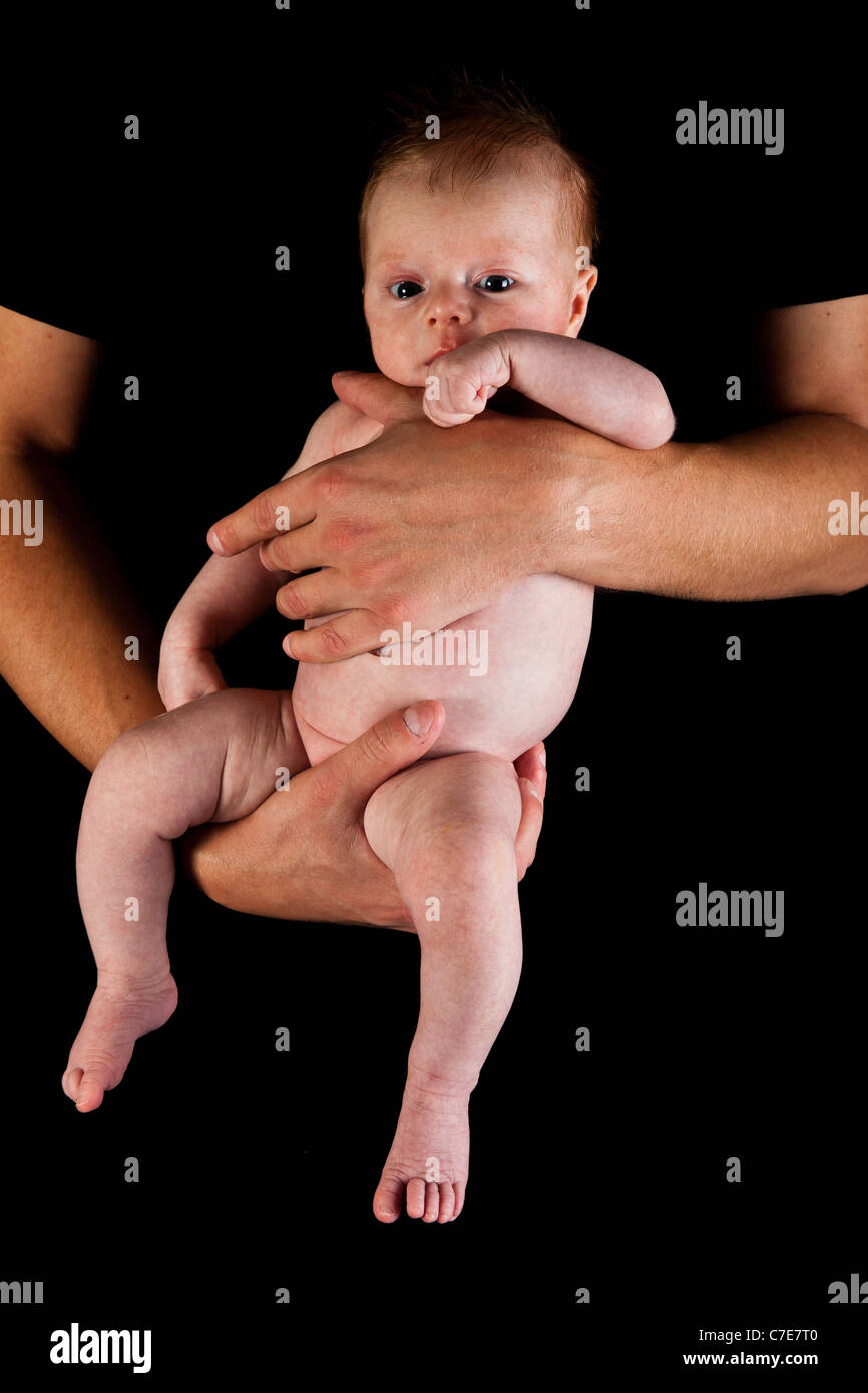 Sur les bras du nourrisson pères isolés sur noir Banque D'Images