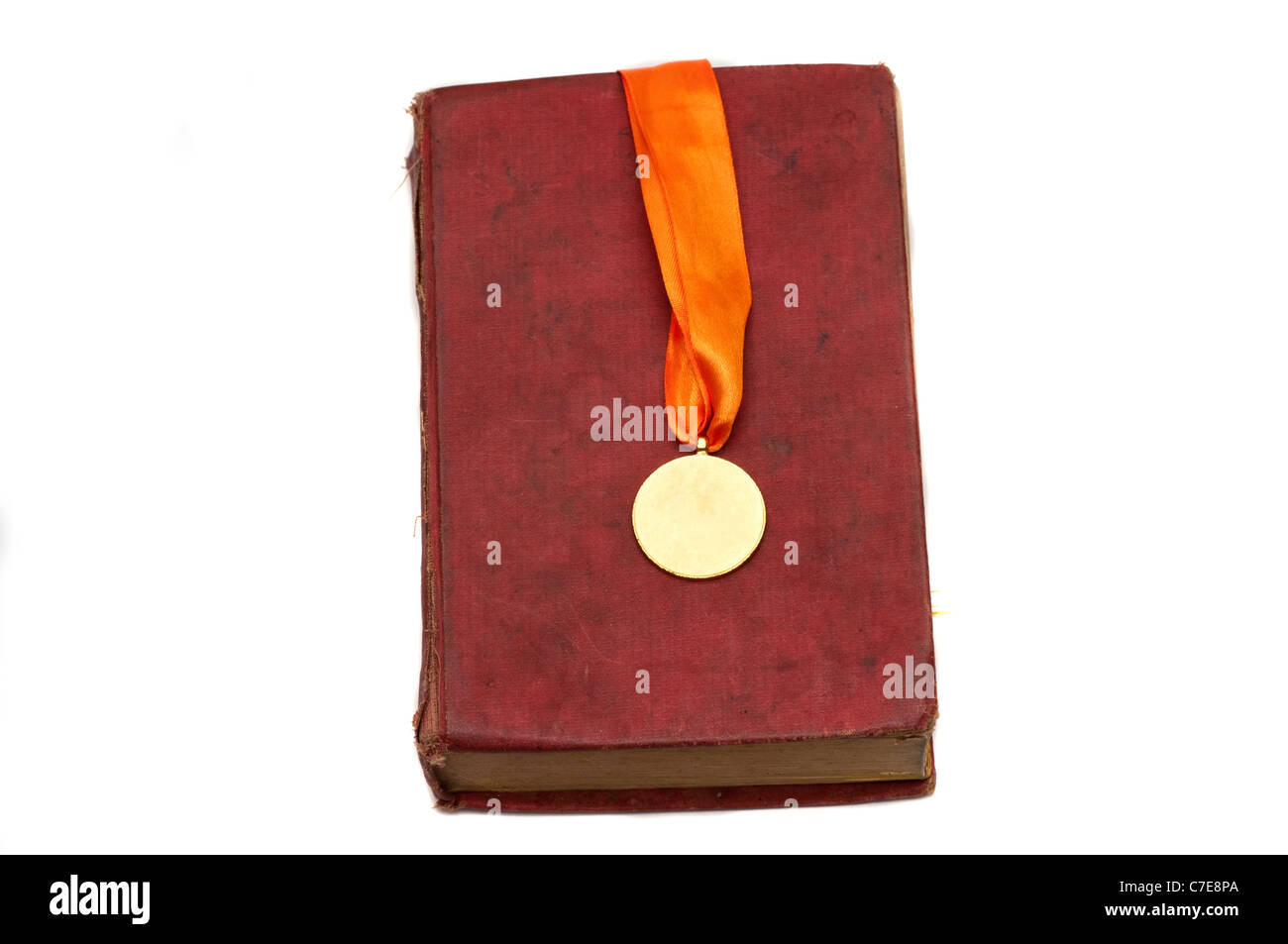 Une médaille d'or sur un livre rouge isolated on white Banque D'Images