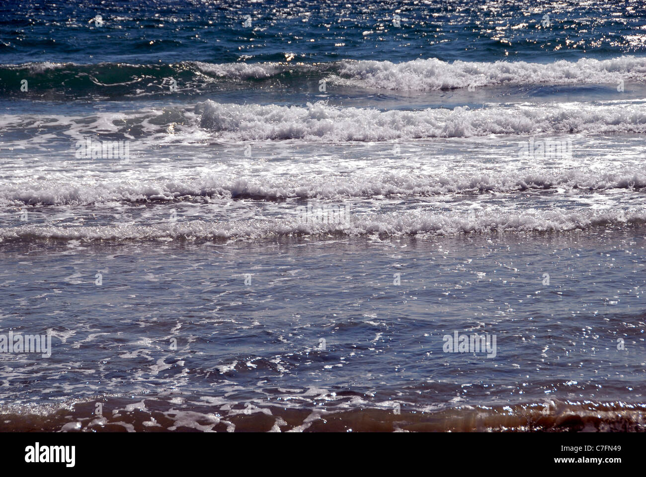Petites vagues miroitant dans la lumière du soleil dans le nord du Pays de Galles Banque D'Images