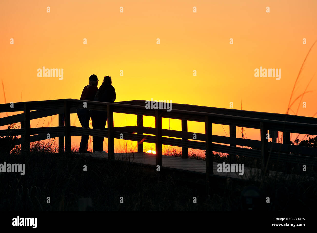 Silhouette de deux personnes regardant le coucher du soleil de la promenade sur la plage en Floride, USA. Banque D'Images