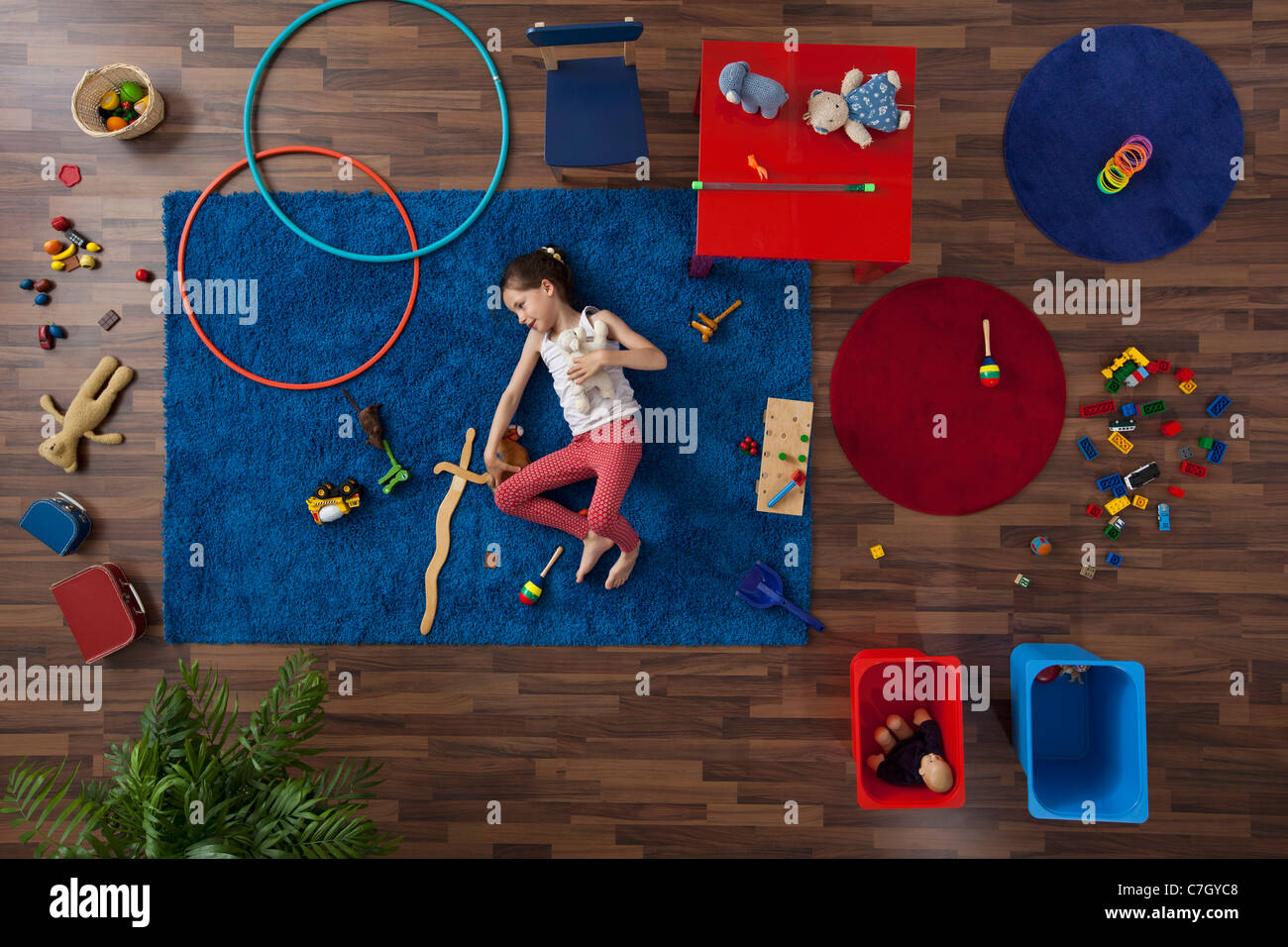 Une petite fille couchée sur un tapis avec des jouets, overhead view Banque D'Images