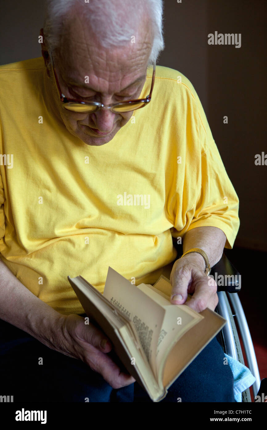 Un homme en fauteuil roulant en feuilletant un livre Banque D'Images