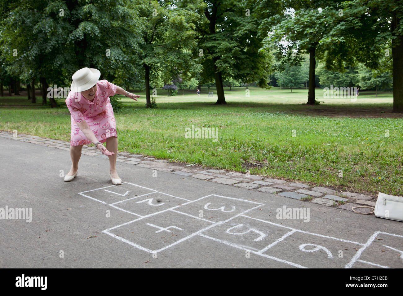 Senior woman roule un pierre comme elle joue à la marelle Banque D'Images