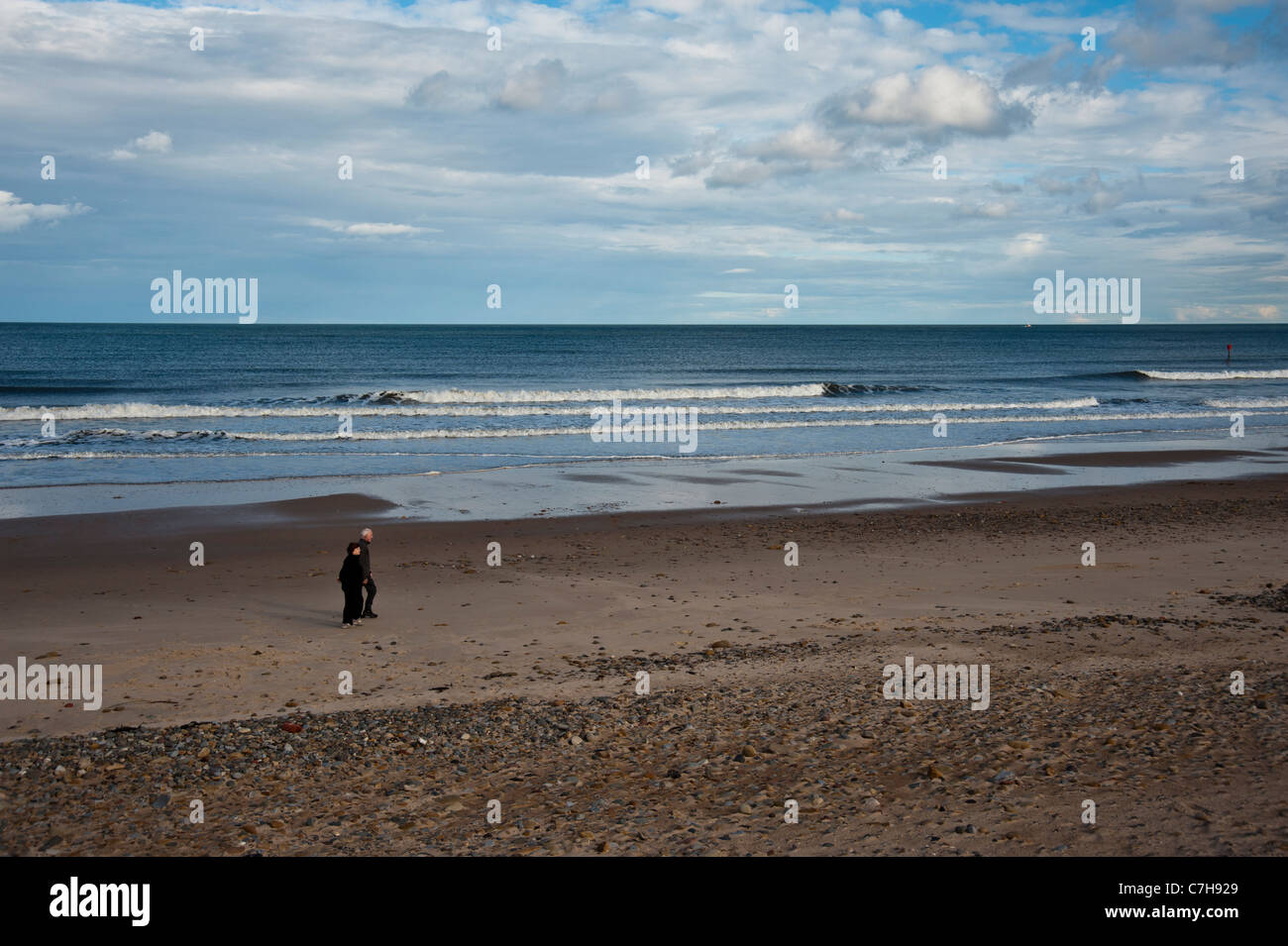 Deux personnes marchant sur une plage déserte à l'automne à Whiteley Bay, près de Newcastle, Northumberland, Angleterre Banque D'Images