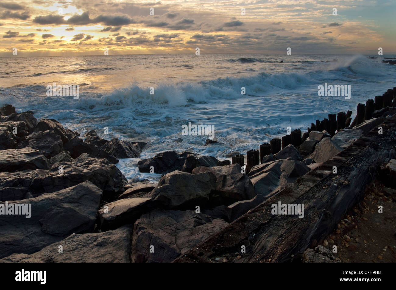 En mer, les vagues se brisant sur les rochers au lever du soleil à Long Branch, NJ Banque D'Images