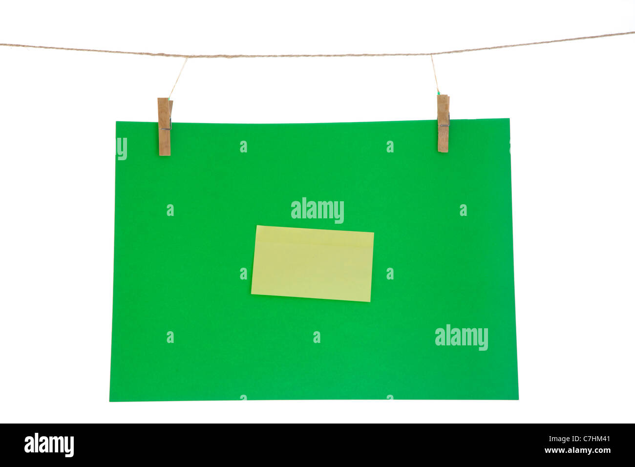 Feuille de papier vert et jaune sur une corde à linge. Isolé sur fond blanc. Banque D'Images