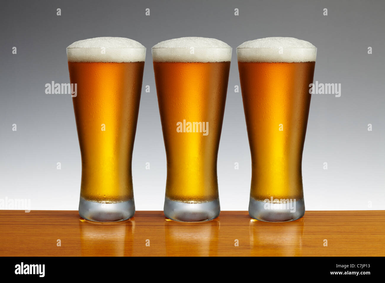 Trois pintes de bière blonde sur une barre en bois haut Banque D'Images