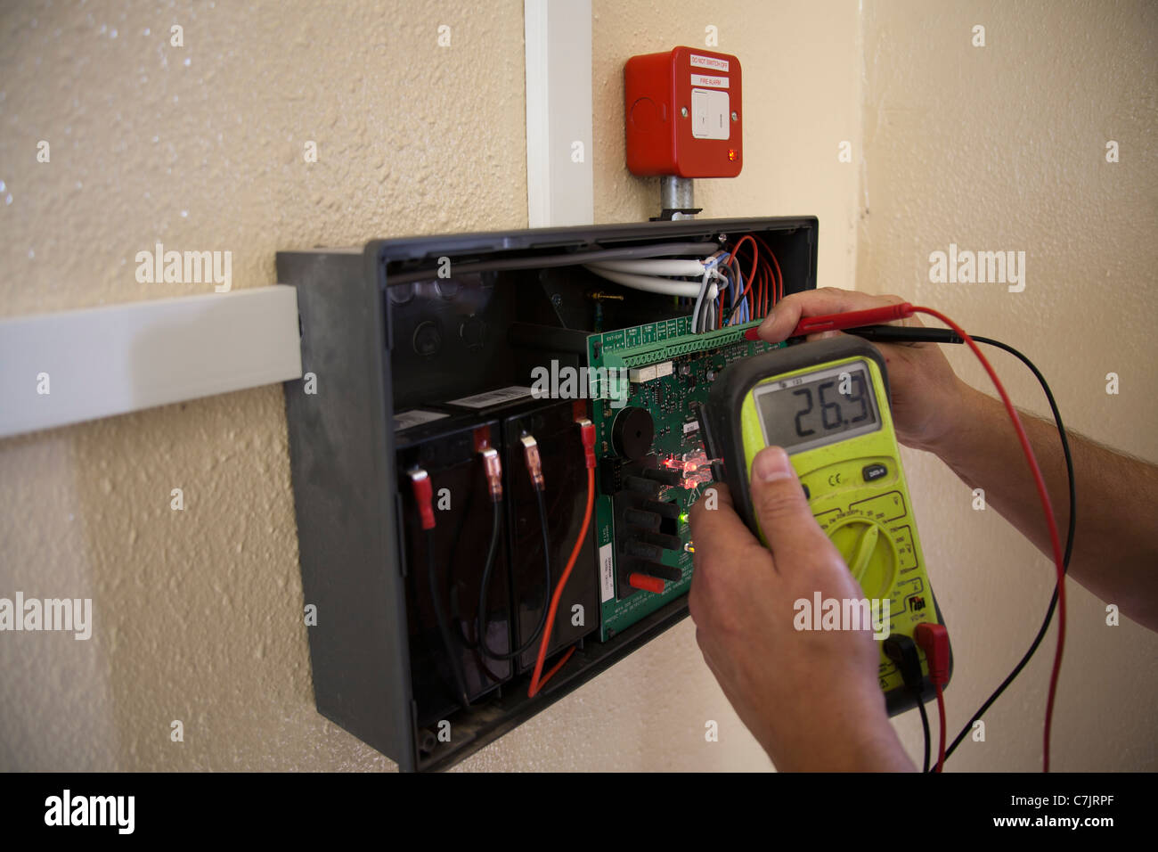 L'équipement de mesure à l'aide électricien   Un diagnostic sur un panneau d'alarme incendie de la propriété et des bâtiments.   Banque D'Images