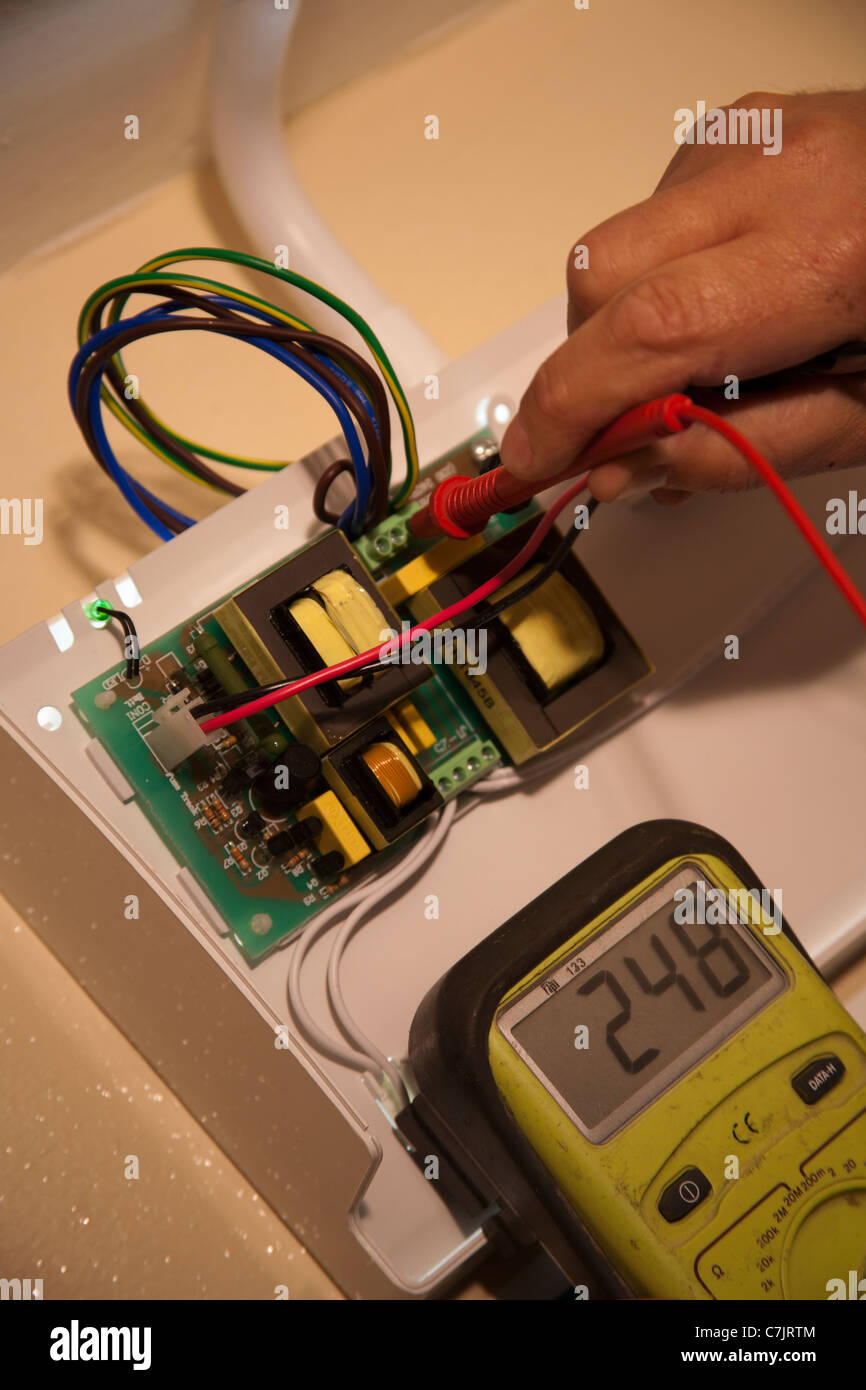 L'équipement de mesure à l'aide électricien   Un diagnostic sur un panneau lumineux d'urgence  Biens et immeubles. Banque D'Images