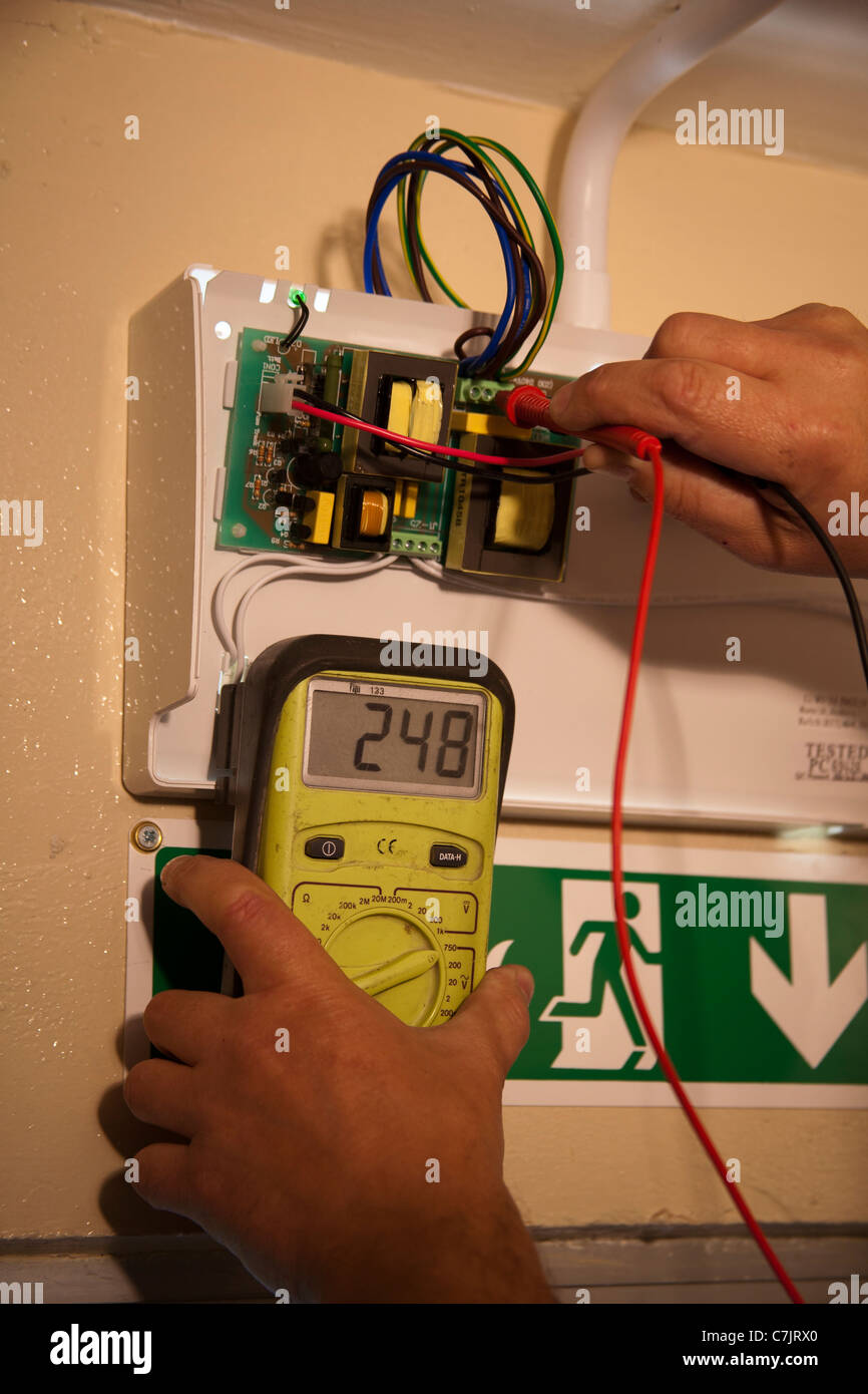 L'équipement de mesure à l'aide électricien   Un diagnostic sur une lumière d'urgence  Biens et immeubles. Banque D'Images