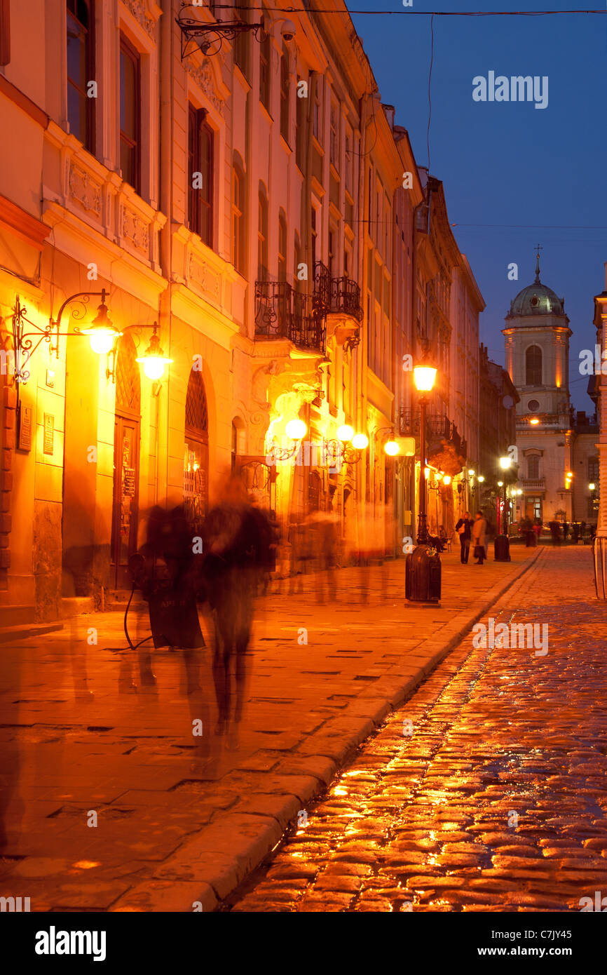 Les piétons marcher la nuit sur la place du marché à Lviv lumineux Banque D'Images