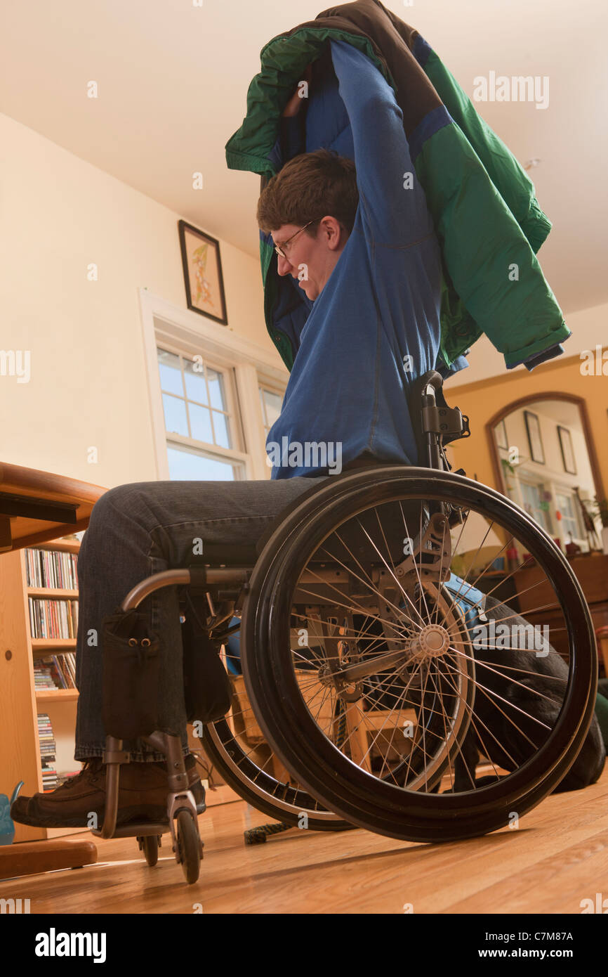 Femme avec la sclérose en plaques dans un fauteuil roulant de mettre son  manteau sans aide Photo Stock - Alamy