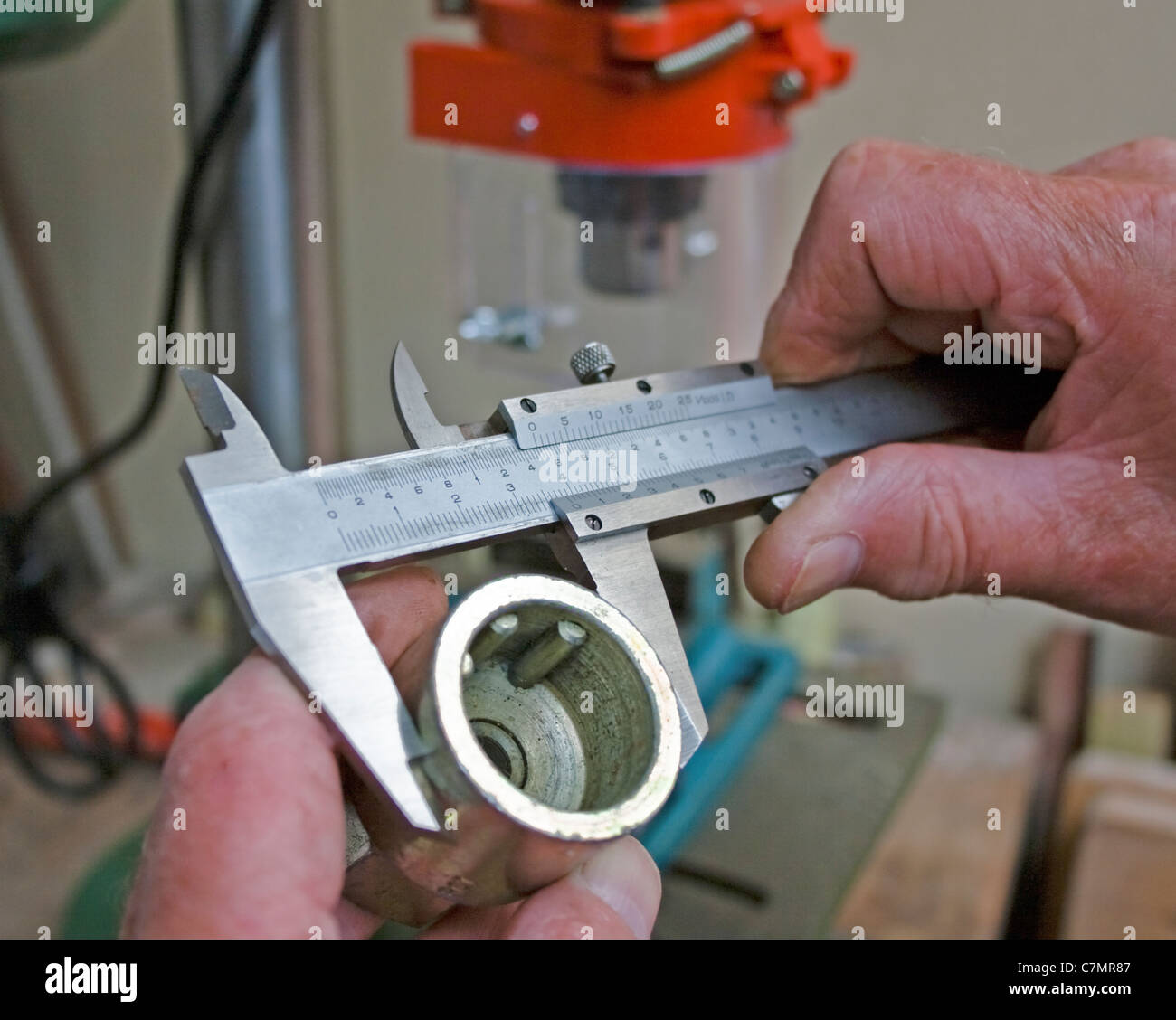 Une image en gros plan montre les mains utilisant des pieds à coulisse pour mesurer une douille, garantissant ainsi la précision de la mesure de l'outil. Les pieds à coulisse sont couramment utilisés pour mesurer les dimensions internes et externes avec une grande précision. Banque D'Images